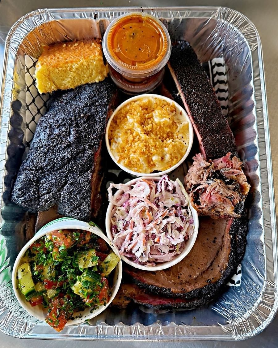 A HaBBQ tray of brisket, ribs and pulled pork with corn bread, mac and cheese, coleslaw and Mediterranean salad