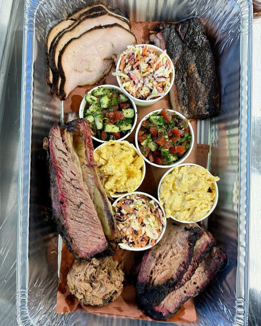 A large catering spread of smoked turkey, brisket and pulled pork with sides